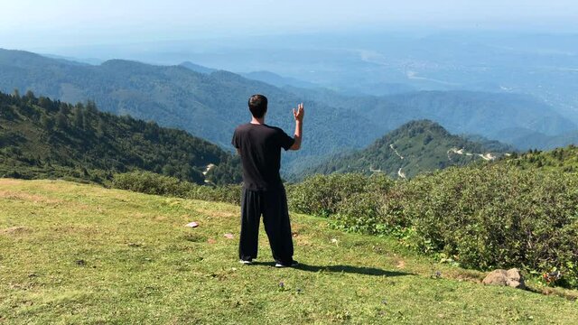 Male Practice Tai Chi with a Mountain View. Man Doing Meditation Practice Alone in a Peaceful Place.