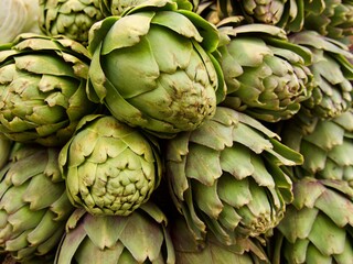 Obraz premium Fresh artichokes at green grocery on Mediterranean street market, southern Europe