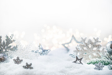 Christmas silver decorations on snow with fir tree branches and christmas lights. Winter Decoration Background
