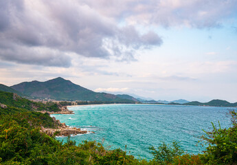 Expansive view of scenic tropical bay, lush green woodland and blue waving sea. The easternmost coast in Vietnam, Phu Yen province between Da Nang and Nha Trang.