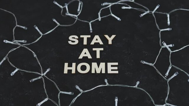 holidays in lockdown due to covid, multicolour Christmas fairy lights surrounding message about staying at home