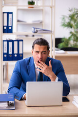 Young handsome employee sitting in the office