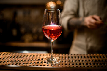 wine glass with bright red transparent drink stands on the bar counter.