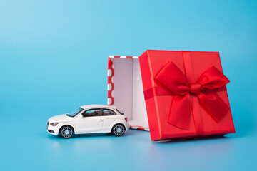 Giving and receiving gifts concept. Close up photo of white toy car beside open red giftbox with...