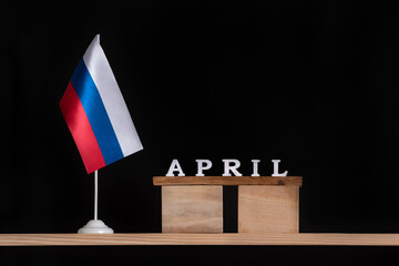 Wooden calendar of April with Russian flag on black background. Dates in Russia in April