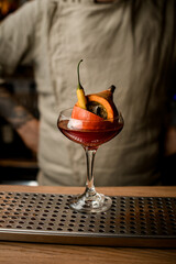 beautiful glass with small pumpkin and pepper inside it stands on the bar counter
