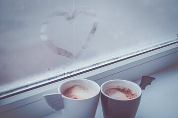 Two cups of coffee by the window. Cups of an angel and a demon. - 392592403