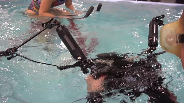 Underwater photography. The girl takes off the aqua trainer for classes in the pool