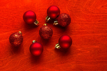 Christmas or New Year composition. Red Christmas balls on a red wooden background with copy space.
