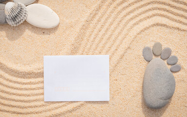 Arrière-plan grains de sable de mer, sable fin de plage avec enveloppe et galets. Emplacement pour texte. Galets en forme de petit pied pour annoncer une naissance.	