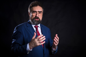 Mature businessman dressed in blue suit with red tie studio portrait.