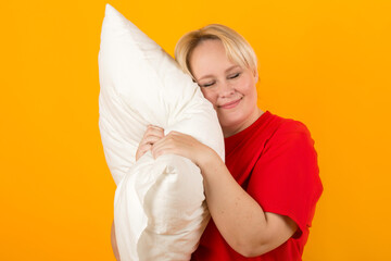beautiful young plump female in a red t-shirt on a yellow background with a pillow
