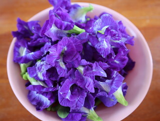 Blue butterfly pea flowers on the plate place on a wooden table