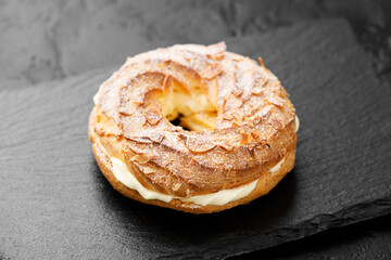 Homemade choux pastry cake Paris Brest with almond flakes and sugar powder.	