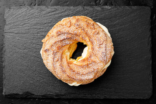 Homemade choux pastry cake Paris Brest with almond flakes and sugar powder. top view	