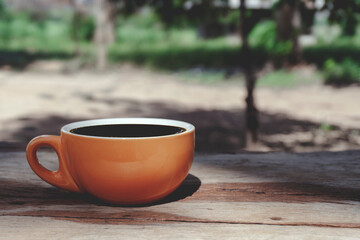 Hot black hot drink coffee big cup Ceramic brown glass placed on an outdoor wood table. The background is a landscape of nature.