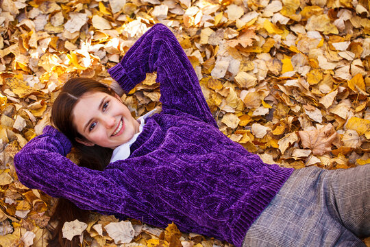 Portrait of a beautiful young woman on the background of autumn yellow leaves, outdoors