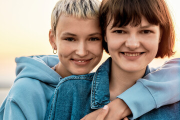 Cropped portrait of two attractive young women with short hair smiling at camera, Young lesbian couple spending time together