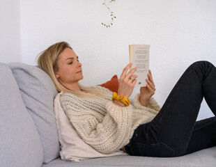 junge Frau liest entspannt auf der Couch