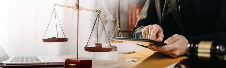 Justice and law concept.Male judge in a courtroom with the gavel, working with, computer and docking keyboard, eyeglasses, on table in morning light