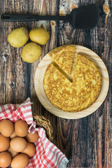 Spanish omelette on a round table with eggs and potatoes