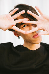 Portrait of young asian man with hands near his face 