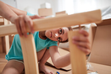Obraz premium Small girl assembling furniture in new apartment, moving in and being hardworking.