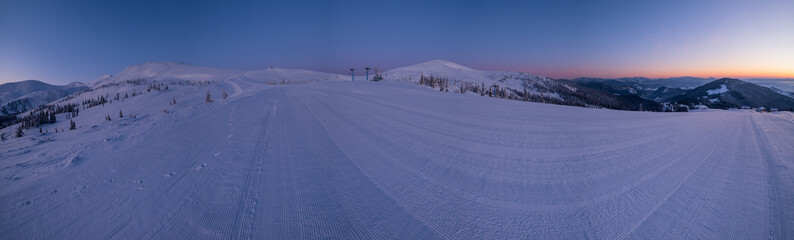 Alpine resort prepared ski slopes and lifts. Pre sunrise morning mountain ridge view. Dragobrat, Ukraine Carpathians.