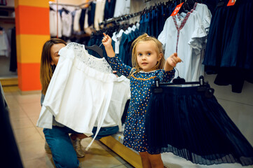Mother and little baby choosing skirt, kid's store