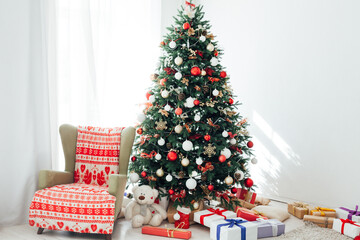 Christmas tree with gifts of garland lights for the new year in the interior of the white room as a backdrop