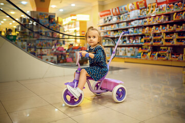 Little baby riding on bicycle in children's shop