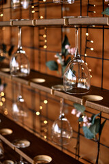 Glasses of champagne hanging over the bar. Wooden stand for wine glasses.  Soft focus.