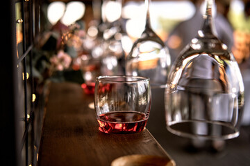 Glasses of champagne hanging over the bar. Wooden stand for wine glasses. The glass is filled with pink champagne. Soft focus.