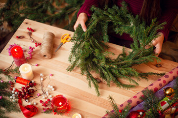 Close-up picture of a Christmas wreath and decorations on a table. Girl making Christmas and New Year decorations with her own hands at home