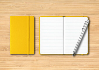 Yellow closed and open lined notebooks with a pen on wooden background