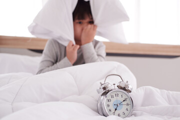 Asian Boy wake up late on seven AM and lazy to go to school. Closed up and focus on clock on white...