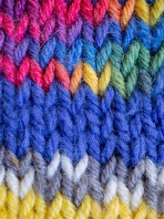 Fototapeta na wymiar blue hand knitting backdrop with blue and rainbow stitches 