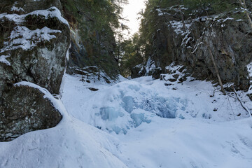 Fototapeta na wymiar Moss Glen Falls in winter after snow storm. Water turned into ice and is covered with a snow. Bright sunny day.