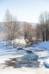 Winter landscape. The stream is covered with ice during the first frost.