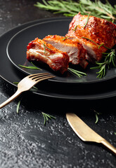 Grilled pork ribs on a black plate.