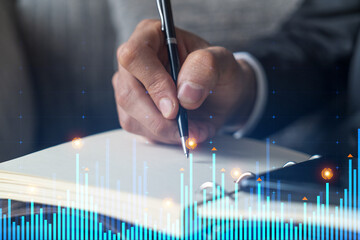 Businessman in suit taking notes. Multiexposure with statistic chart hologram. Man writing down important information in his business diary. Financial trading concept.