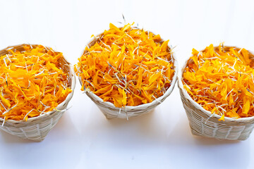 Marigold flower petals in bamboo basket on white background.