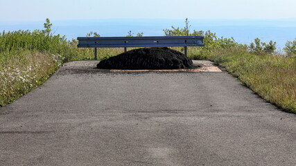 Dead end road in the mountains ending with crash barrier and a pile of gravel.