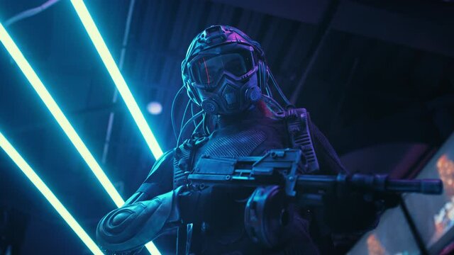 Female soldier of future in fiction helmet with assault gun in her hands backlit with neon street blue lights. Combat cyborg in futuristic protective suit. Cyberpunk warrior, bright night illumination