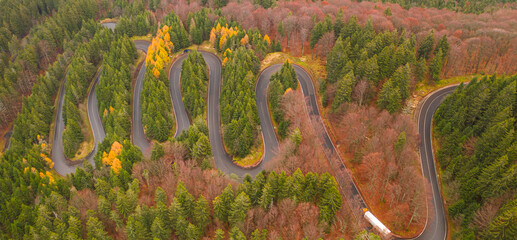 Aerial view of an amazing winding curved road through the mountains in autumn fall colors landscape, motorway in Romania