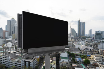 Blank black road billboard with Bangkok cityscape background at day time. Street advertising poster, mock up, 3D rendering. Side view. The concept of marketing communication to promote or sell idea.