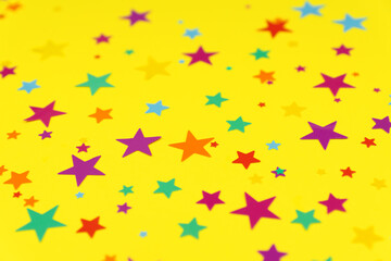 multicolored backdrop of colored stars confetti on a yellow background