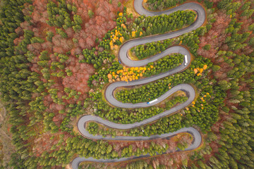 Aerial view of an amazing winding curved road through the mountains in autumn fall colors landscape, motorway in Romania