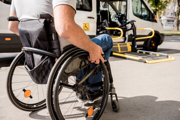 A man in a wheelchair moves to the lift of a specialized vehicle 