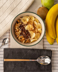Top view of a porridge bowl with banana, kiwi, and a pear.